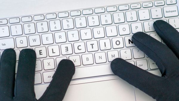 Gloved hands on a keyboard with the word election highlighted