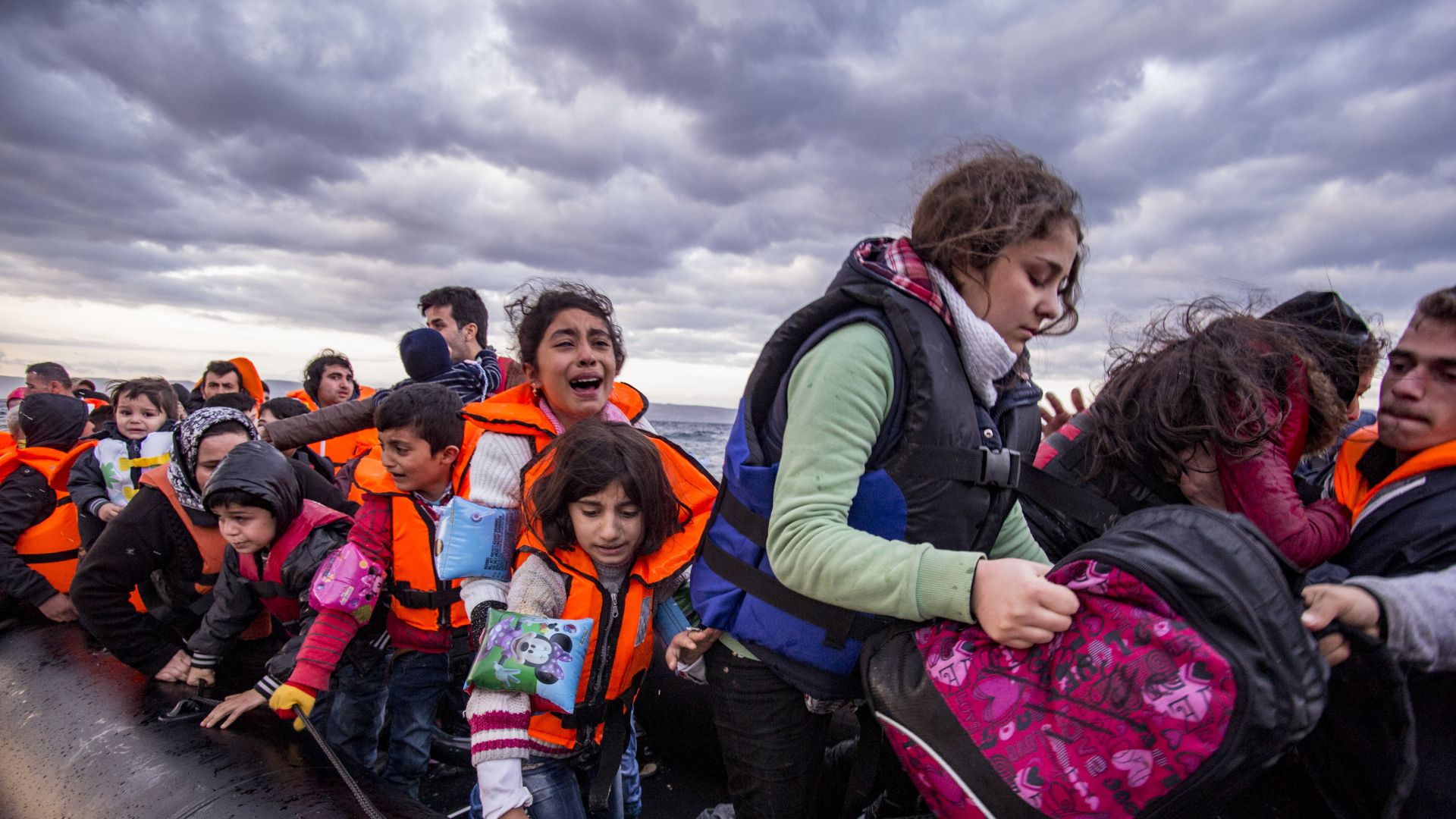 Syrian refugees, with women and children, are helped from a small inflatable boat on arrival in Lesvos