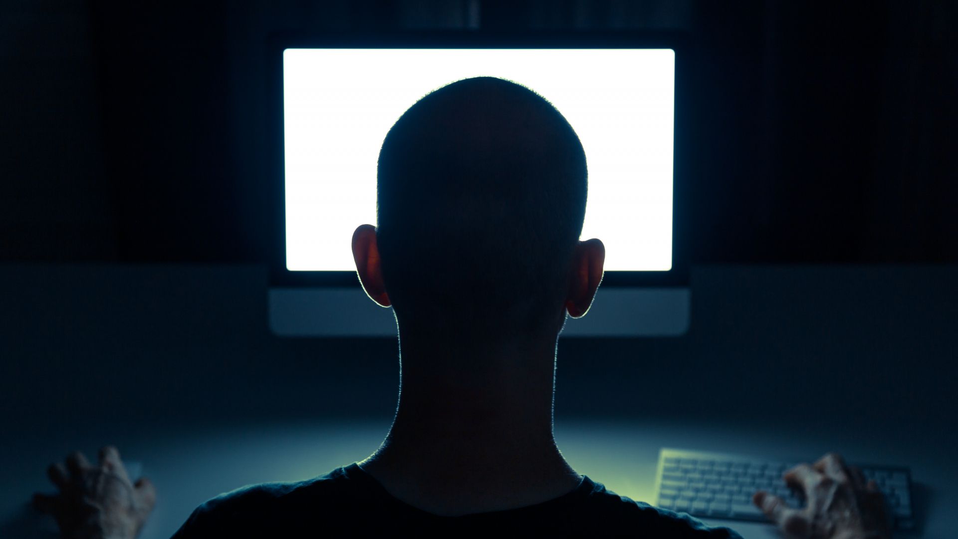 Silhouette of a man using a computer