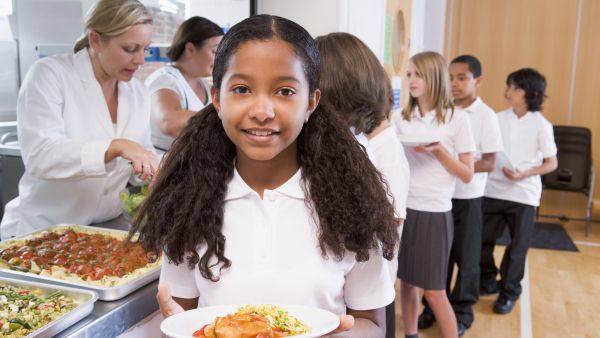 Smiling girl with a plate of food at a school canteen