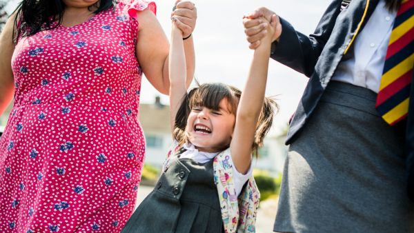 Schoolgirl swinging happily in the air holding hands with her family