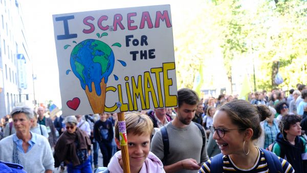 Young protestors carrying a banner saying I scream for the climate with a picture of the world as an ice cream