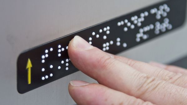 Blind person reading braille note on ATM