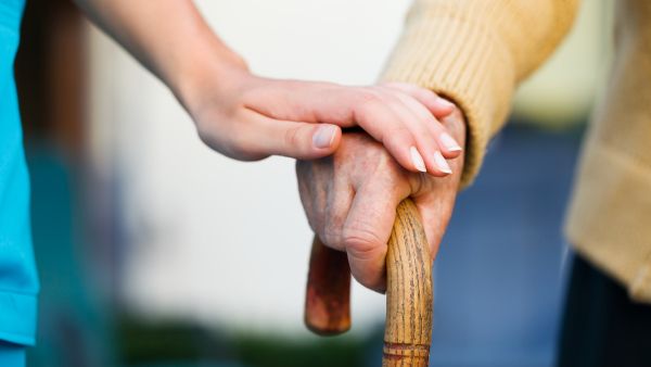 old person leaning on walking stick