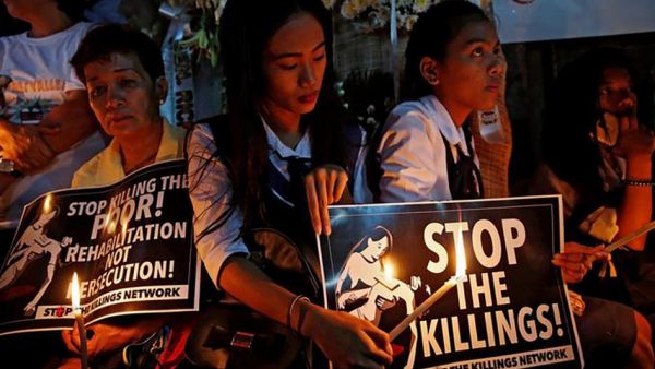 Filipino people holding signs says stop the killings